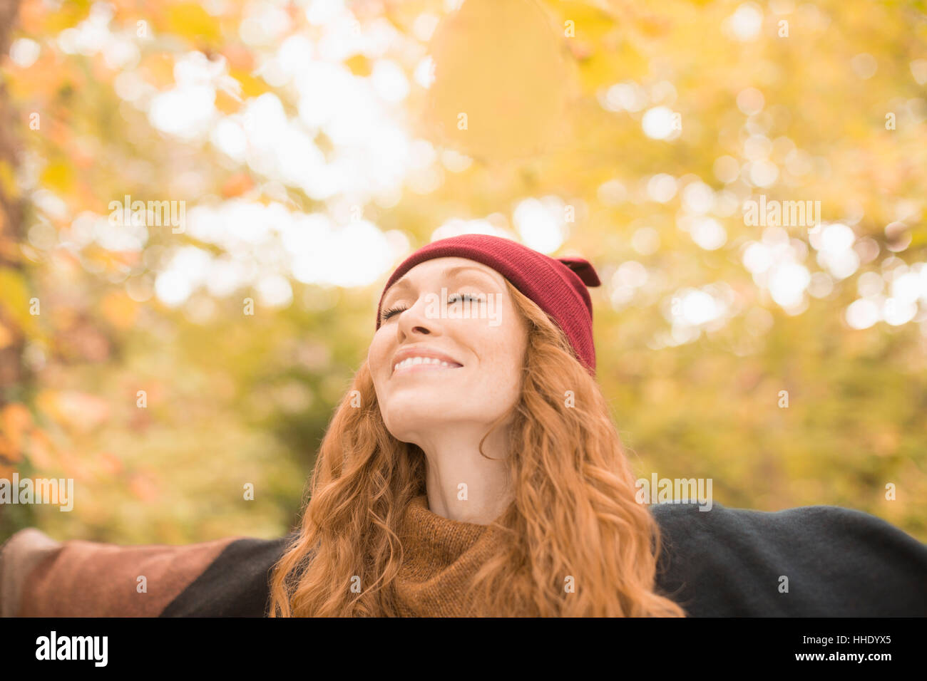 Carefree donna in piedi sotto gli alberi in autunno con le braccia aperte Foto Stock
