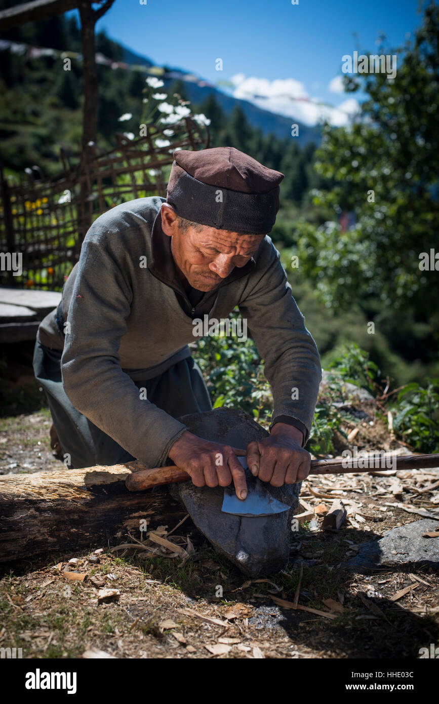 Un Tamang uomo nel Tamang Heritage regione vicino al Langtang aguzza un ax nel modo tradizionale, Regione Langtang, Nepal Foto Stock
