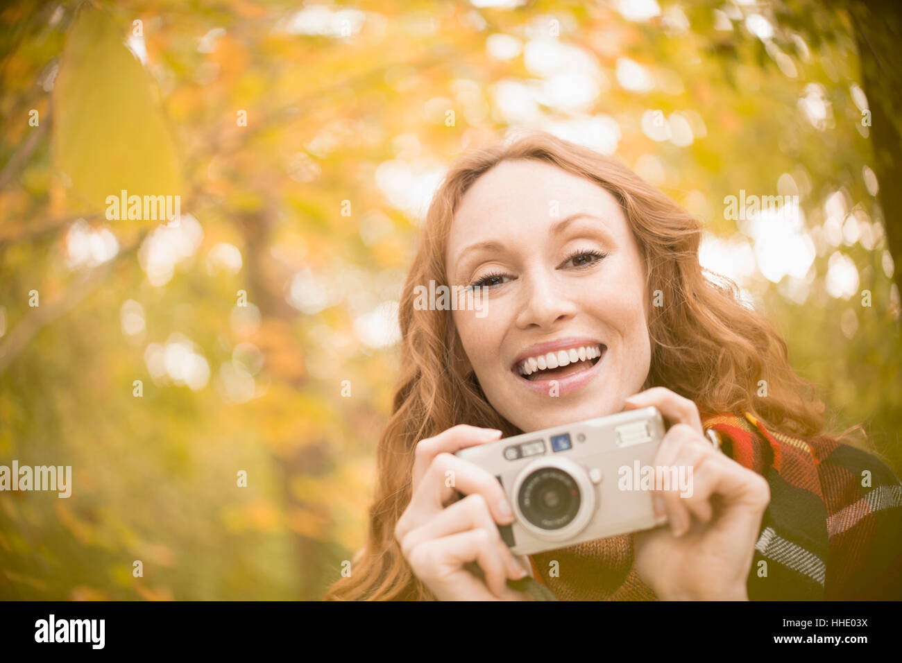 Ritratto di donna entusiasta con fotocamera digitale sotto gli alberi di autunno Foto Stock