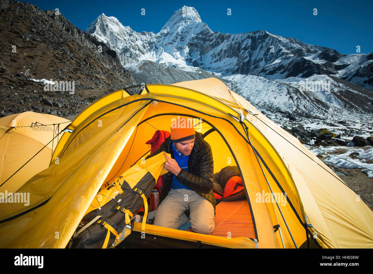 Un alpinista confezioni della sua borsa in preparazione per salire sull'Ama Dablam, 6856m picco nella distanza, Regione di Khumbu, in Nepal Foto Stock