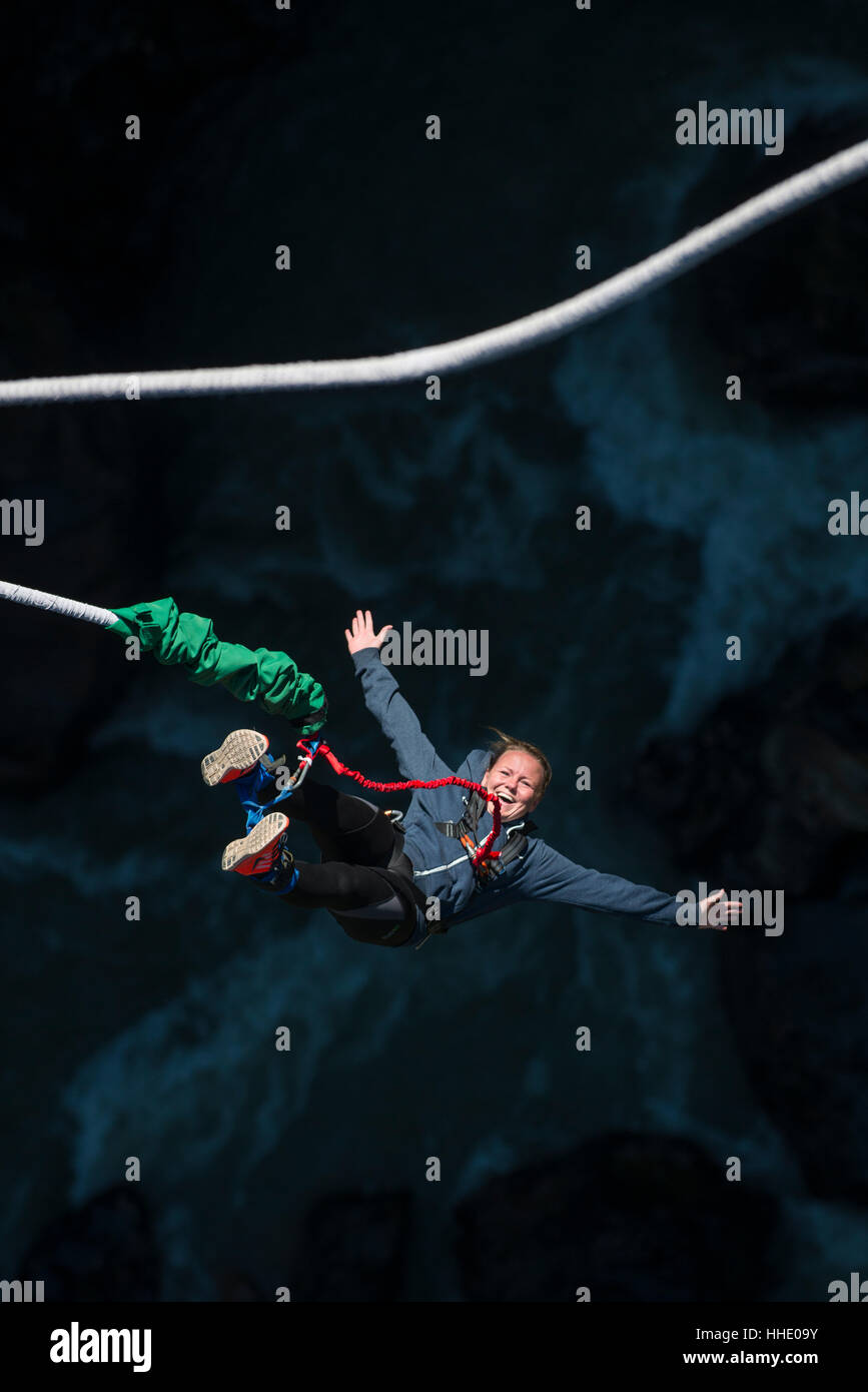 Una donna che sorride per la telecamera come ella è rimbalzato backup durante un bungee jump in ultima istanza, Nepal Foto Stock