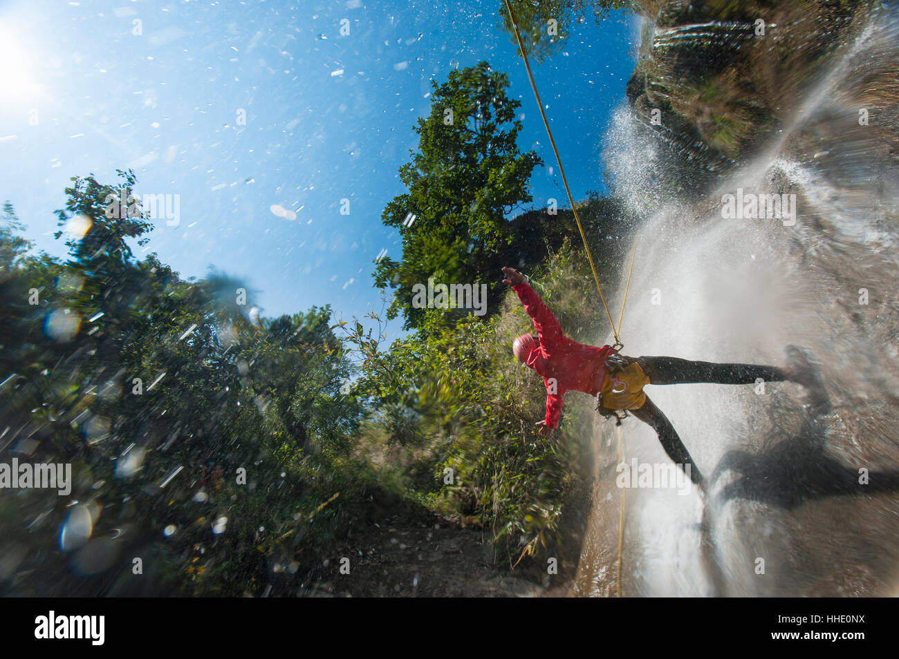 Un uomo si sofferma a tenere le sue braccia a caduta di acqua mentre il canyoning in Nepal Foto Stock