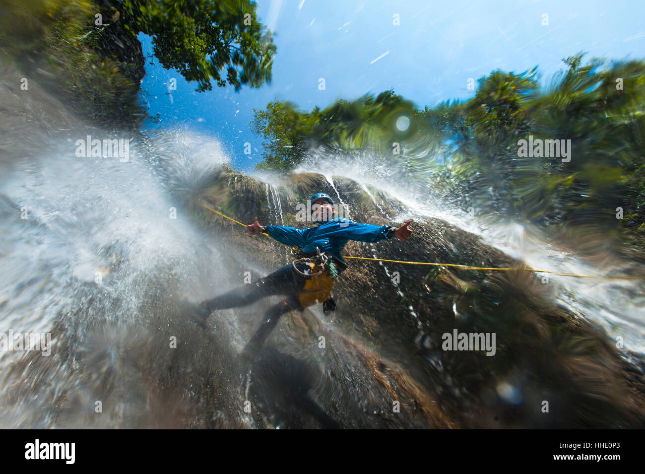 Un uomo si sofferma a sorridere per la fotocamera mentre il canyoning in una cascata, Nepal Foto Stock