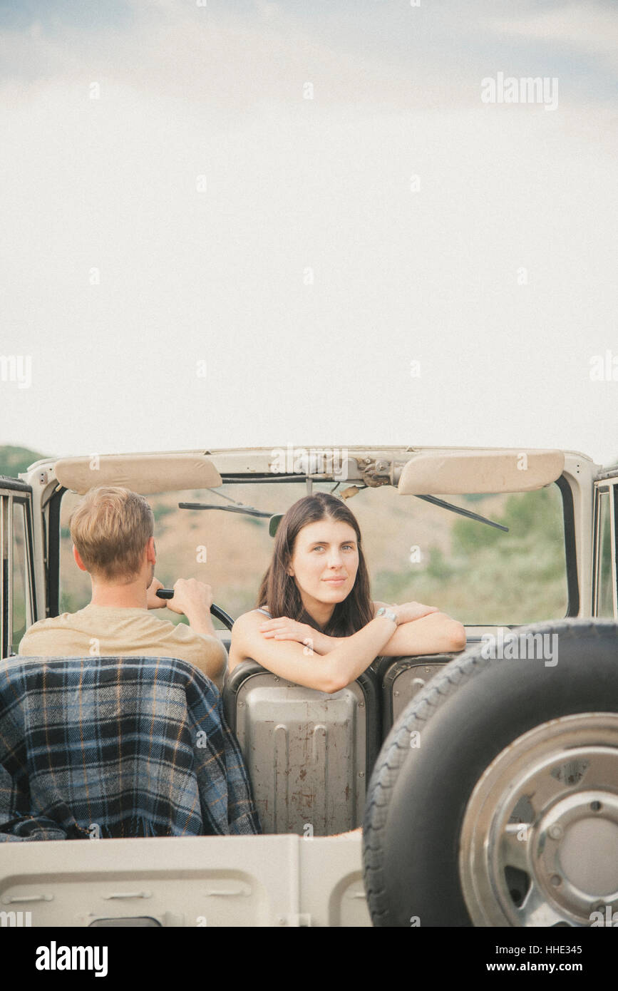 Un giovane su un viaggio in una jeep fianco a fianco, una donna che si guarda alle spalle. Foto Stock