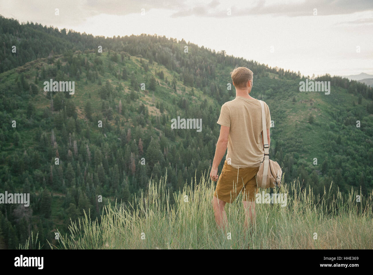 Un uomo in montagna in piedi che guarda intorno a lui. Foto Stock
