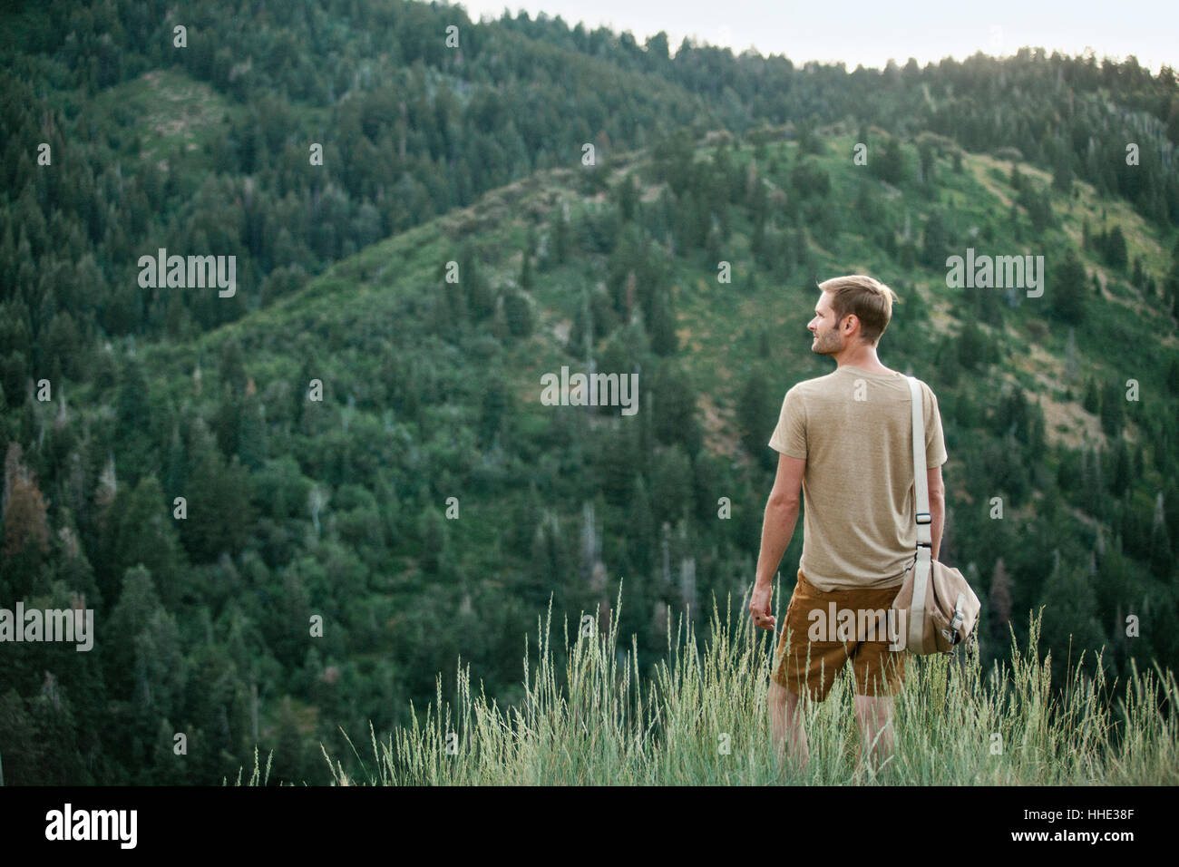 Un uomo in montagna in piedi che guarda intorno a lui. Foto Stock