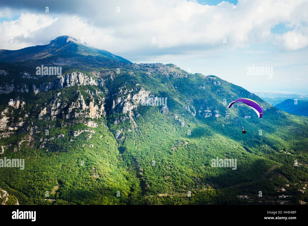 Un parapendio in volo su una valle tra le montagne. Foto Stock