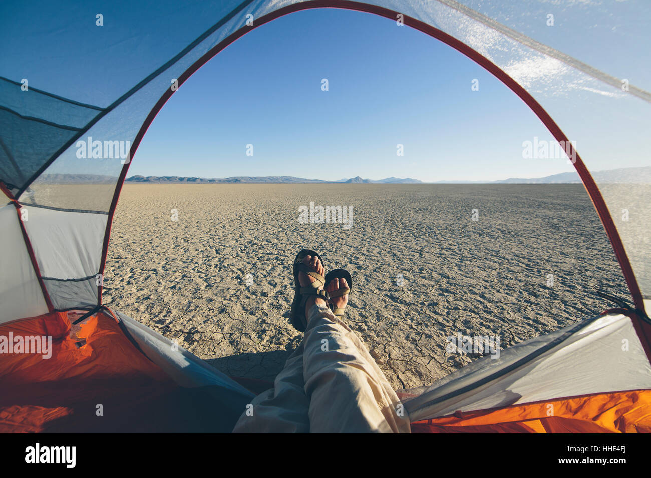 Reclinazione uomo in tenda da campeggio, espansiva di deserto e di playa in distanza, Black Rock Desert, Nevada Foto Stock