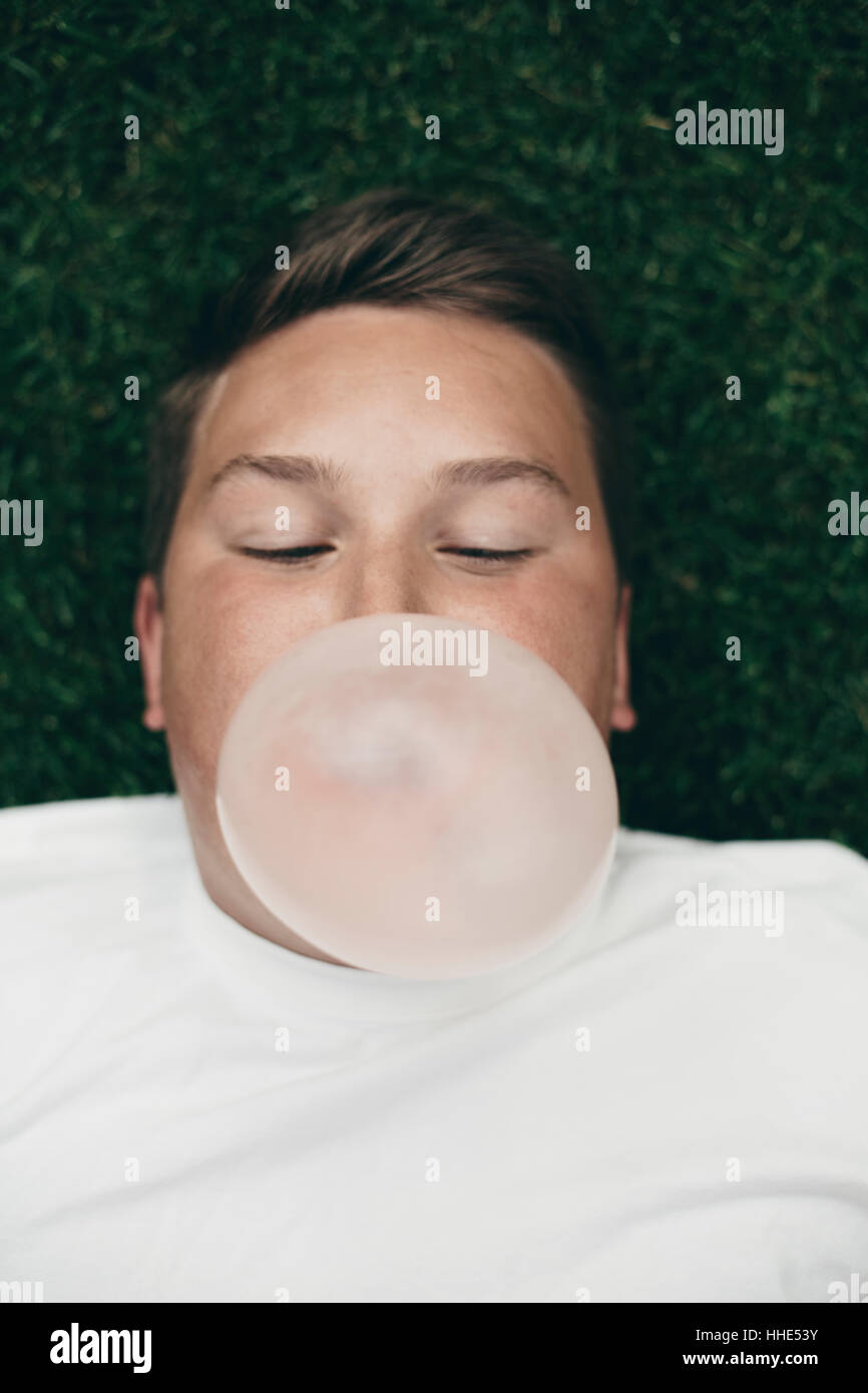 Ritratto di ragazzo adolescente soffiando bubble gum bubble Foto Stock