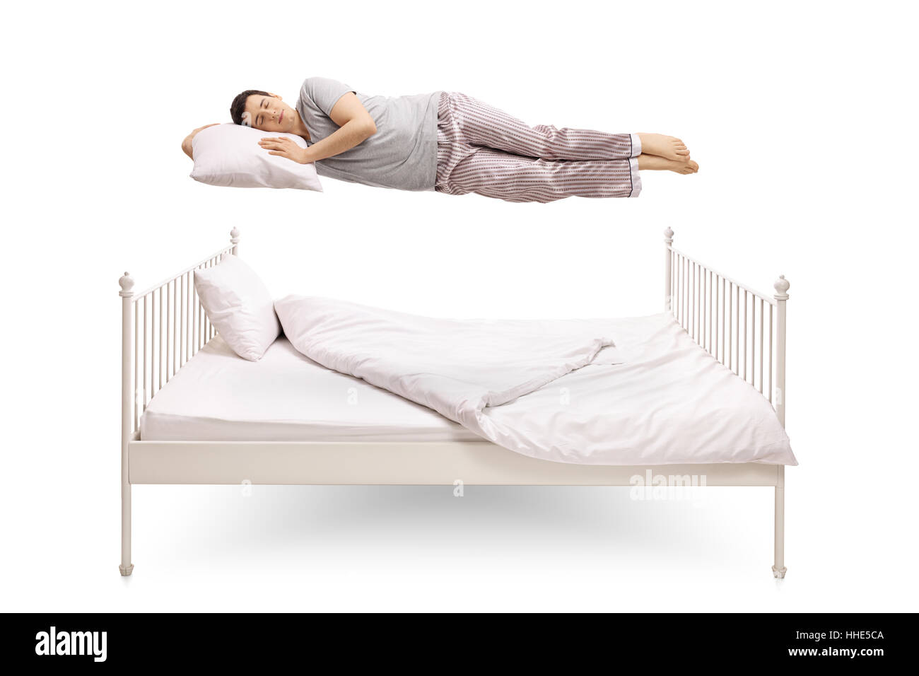 Giovane uomo dorme e galleggiante sopra un letto isolato su sfondo bianco Foto Stock