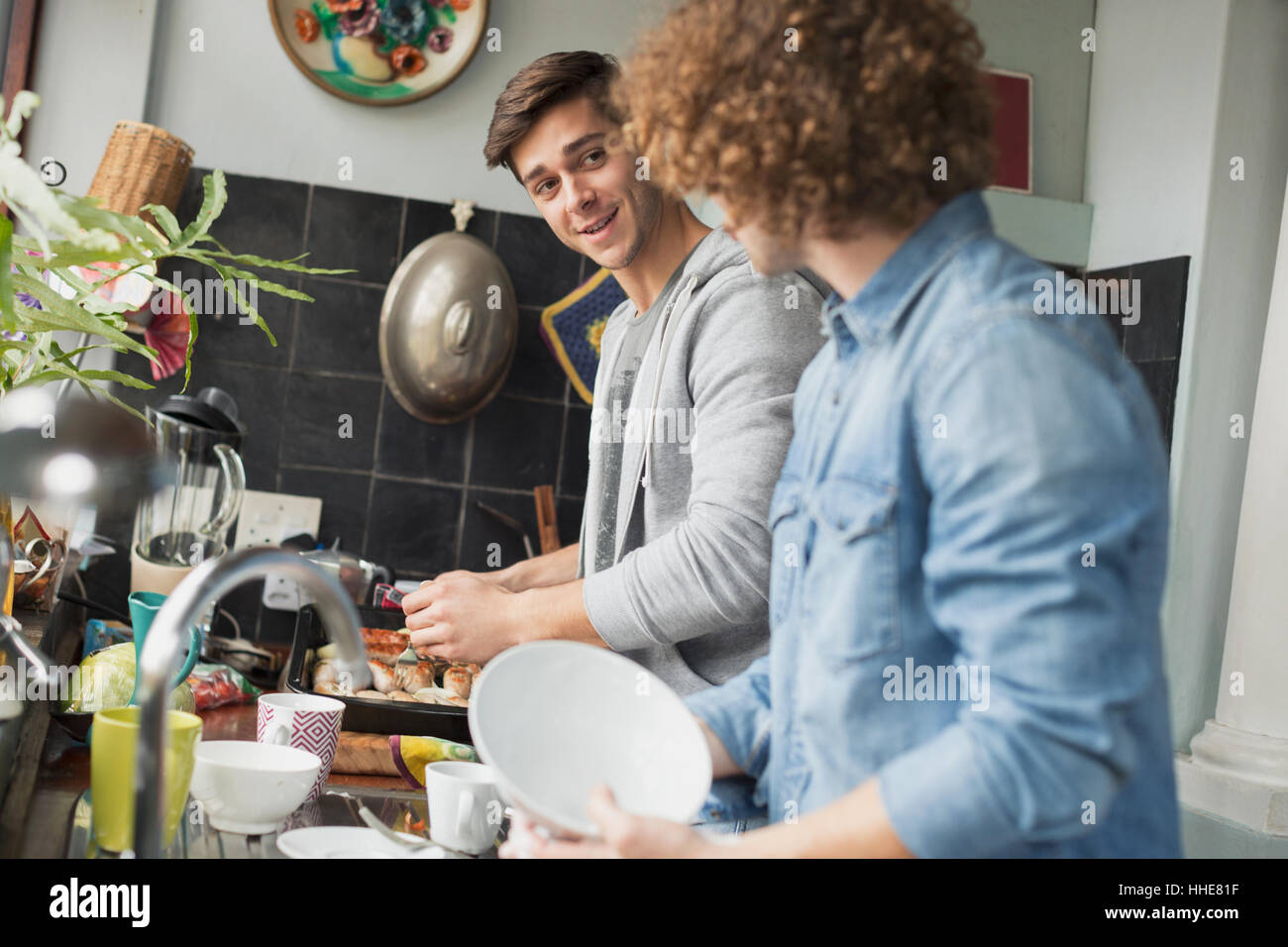 Giovani uomini coinquilini di cottura e fare piatti in cucina Foto Stock