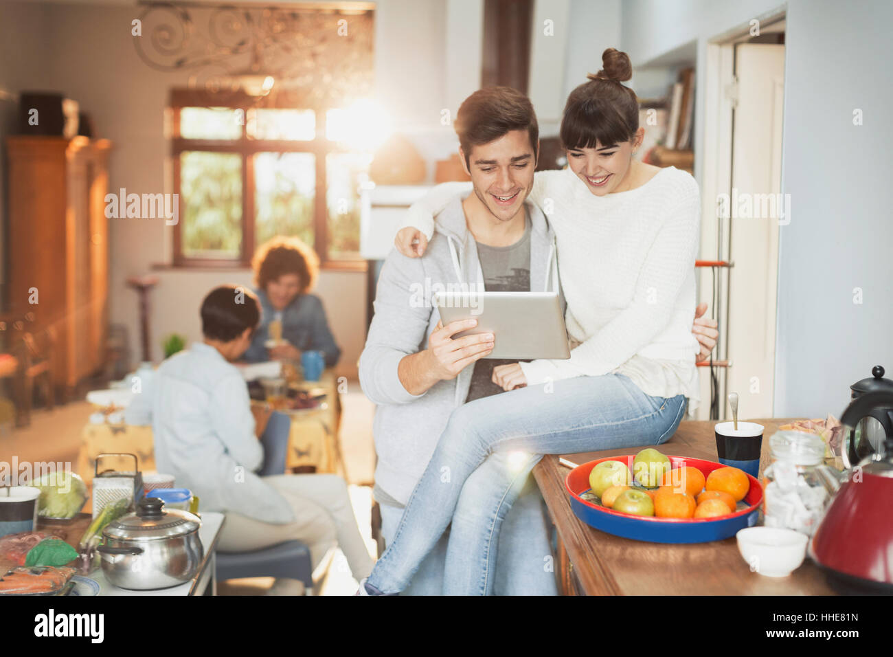 Sorridente coppia giovane con tavoletta digitale in cucina Foto Stock