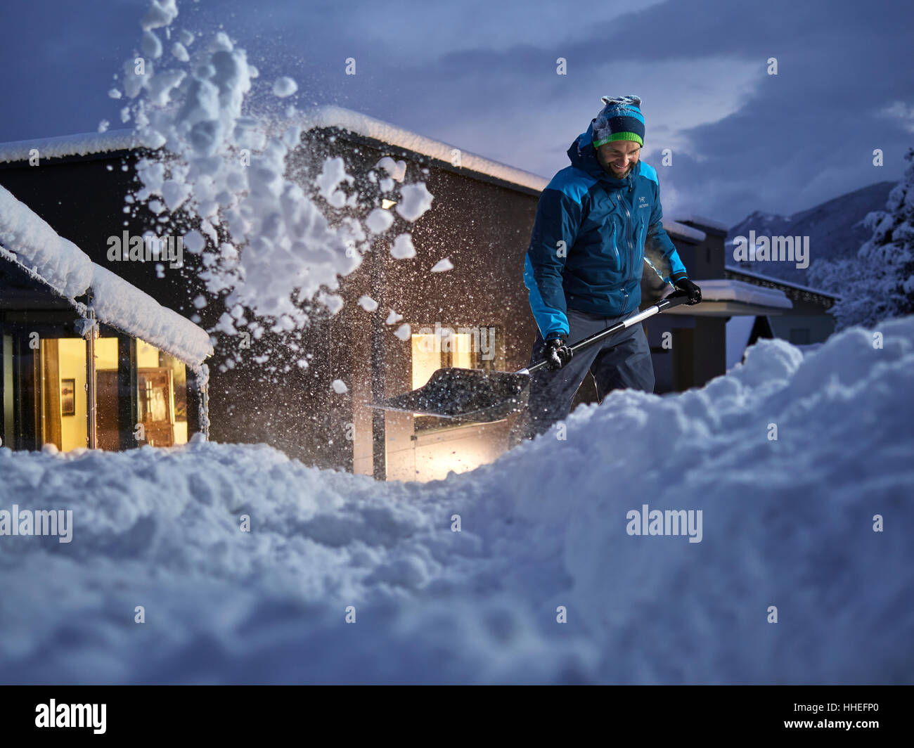 L'uomo, 35-40 anni, spalare la neve al crepuscolo, Kolsass, Tirolo, Austria Foto Stock