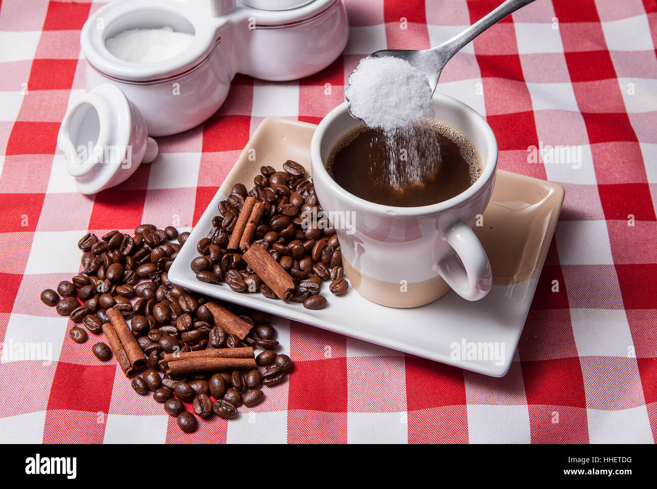 Versare lo zucchero in tazza di caffè. Foto Stock