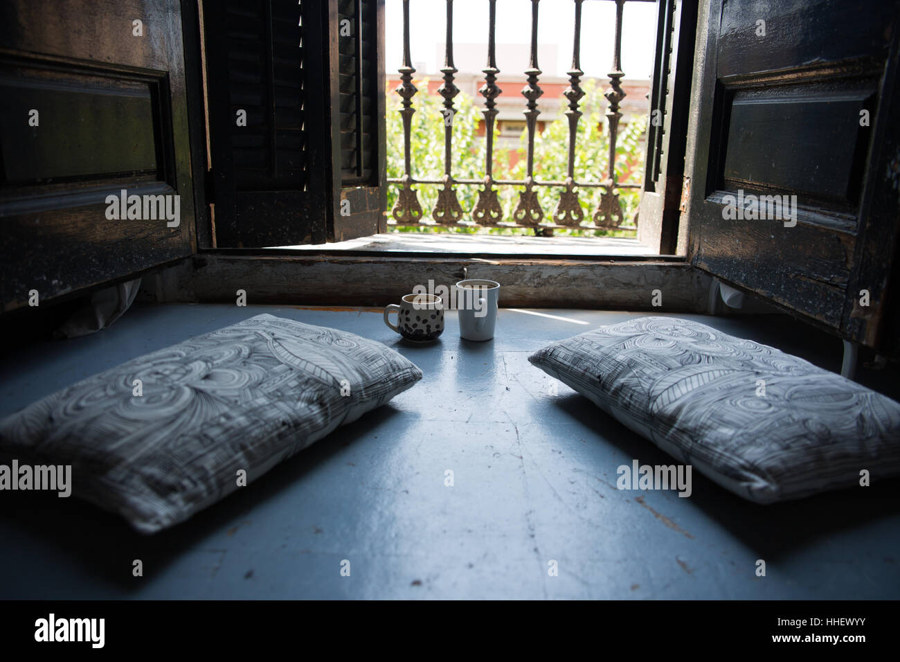 Una bella scena bohemien di due tazze e due cuscini sul pavimento con un balcone vista in un artistico piatto in Barcelona Foto Stock