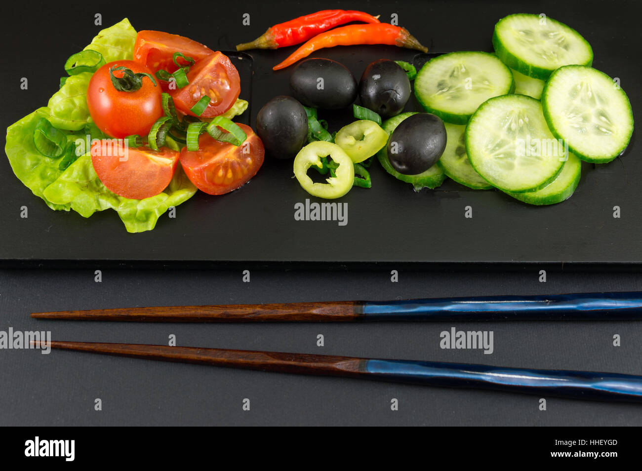 Bacchette e insalata di verdure su sfondo nero Foto Stock