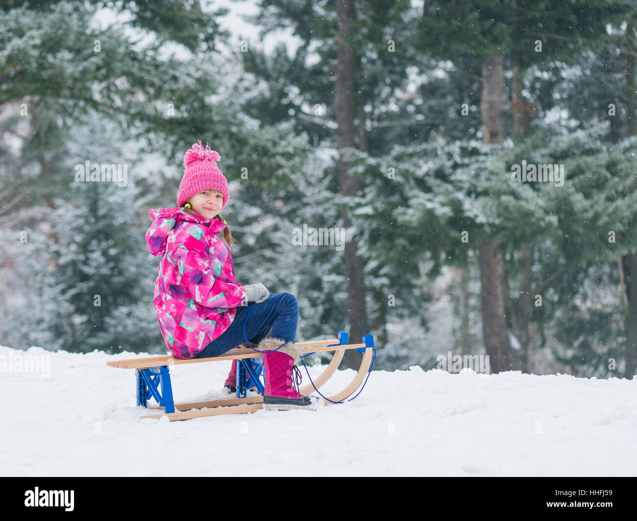 Bambino giocare nella neve con slitta Foto Stock