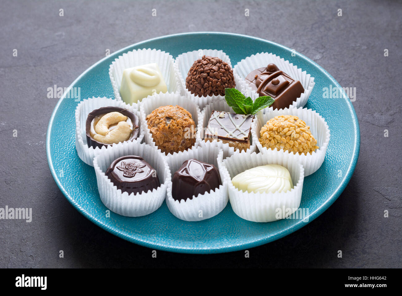 Cioccolatini, Cioccolato raffinato assortimento su piastra blu Foto Stock
