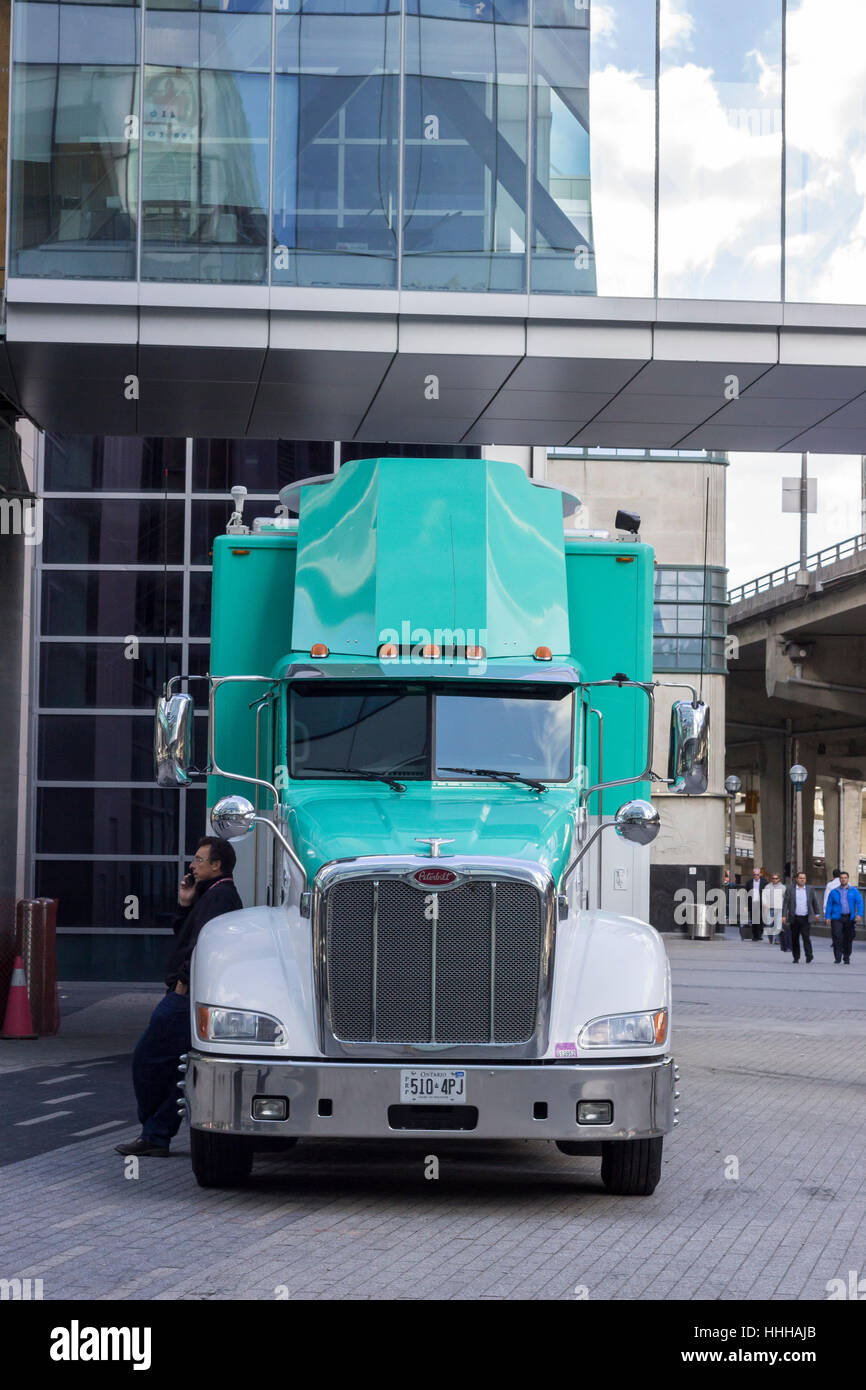 TORONTO, Canada - uomo in piedi vicino al verde oldstyle carrello alla fine di una giornata di lavoro nel centro cittadino di Toronto Foto Stock