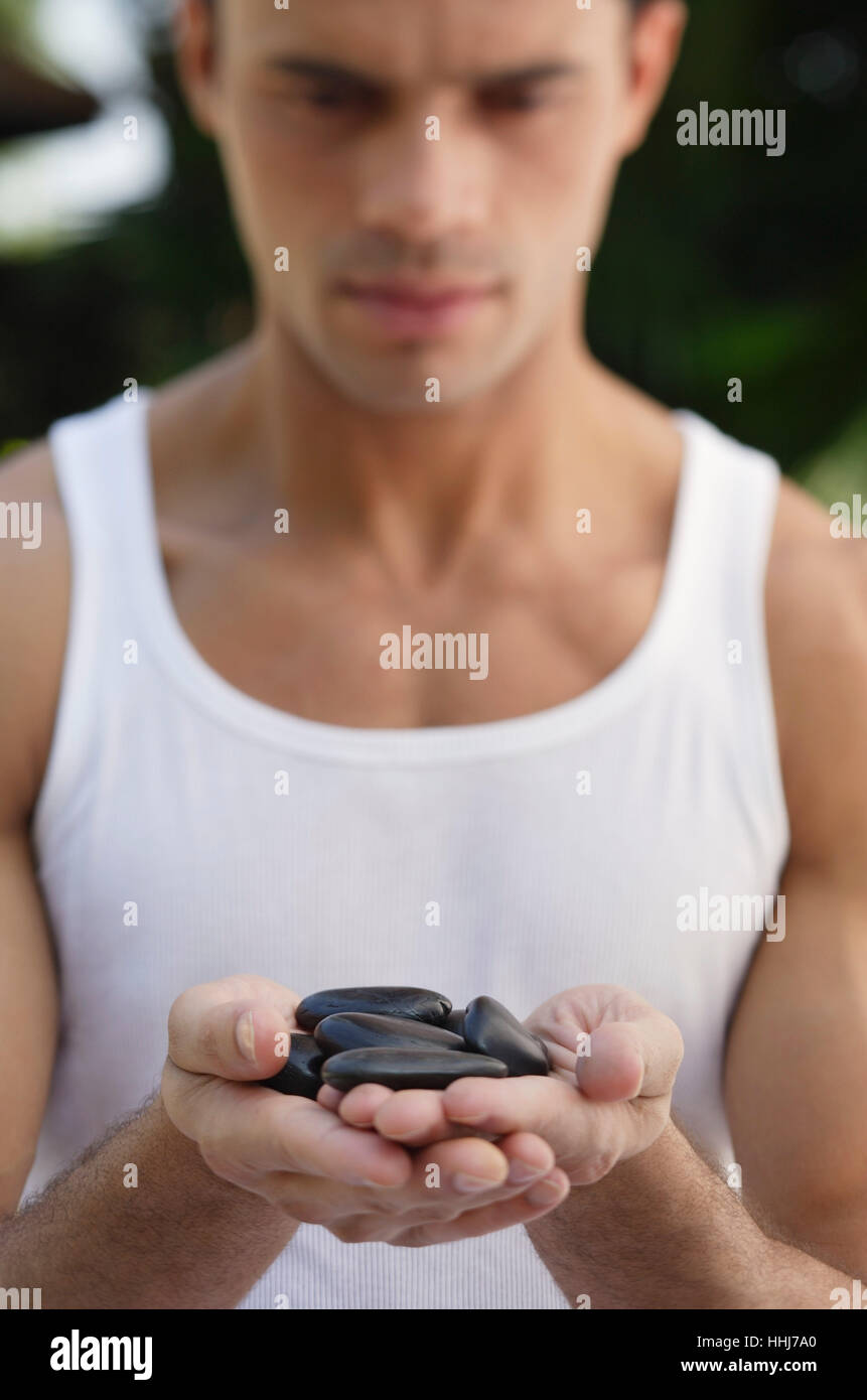Uomo con rocce nel palmo delle mani Foto Stock