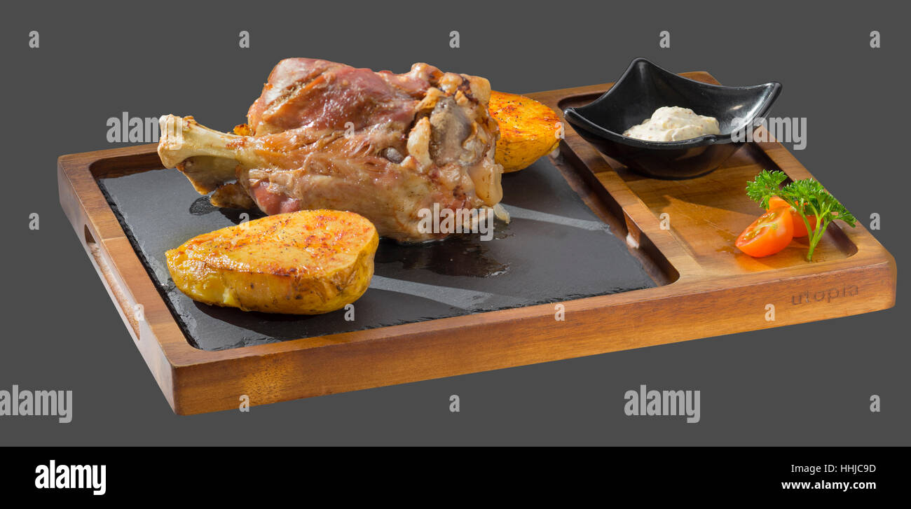Arrosto di maiale il fuso a snodo con guarnite di tostato condito e patate servita in una ciotola di legno e pietra Foto Stock