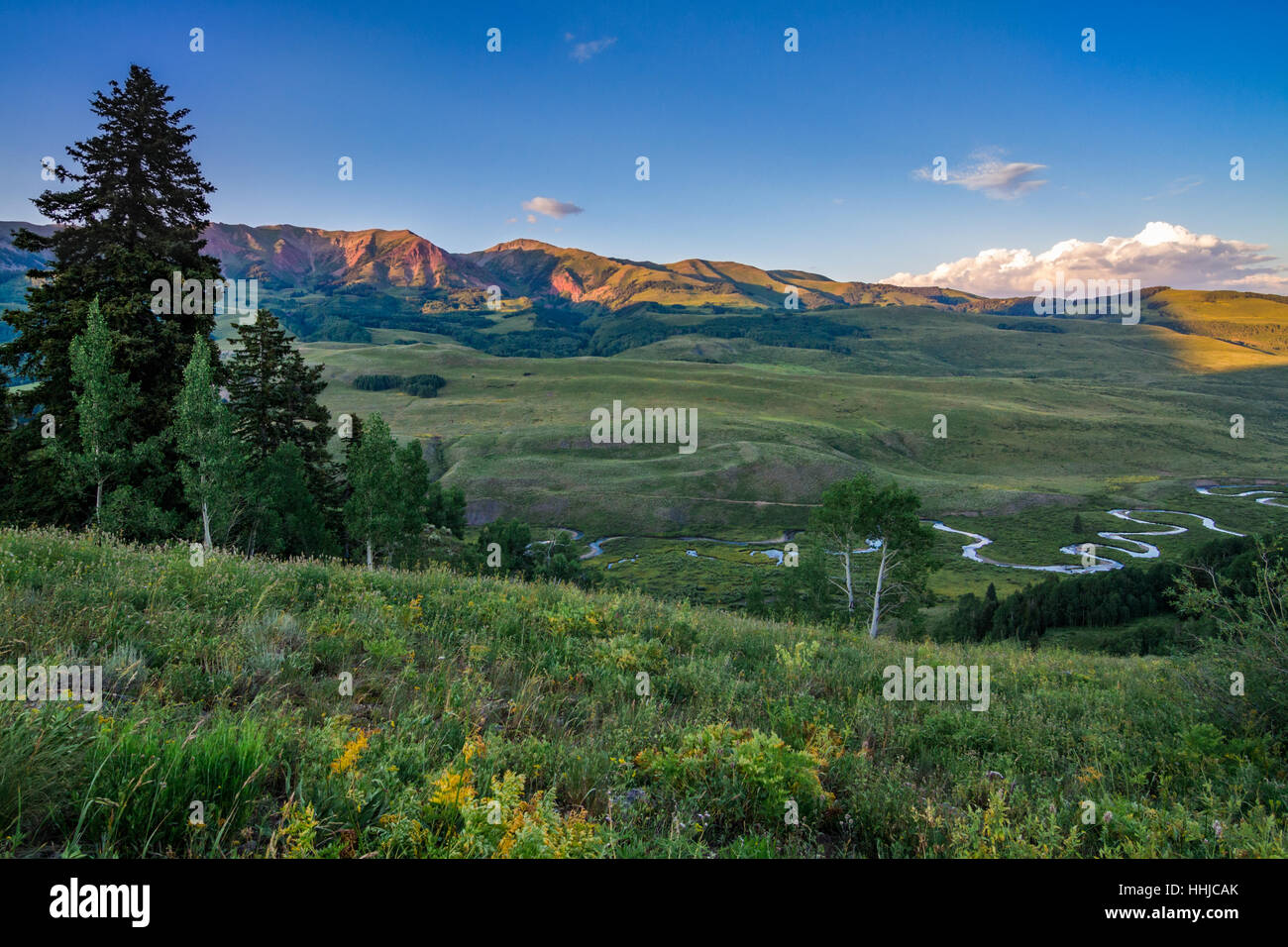 Impostazione sun rende montagne glow rosso al verde dei campi estivi e vagare flusso vicino a Crested Butte, Colorado Foto Stock