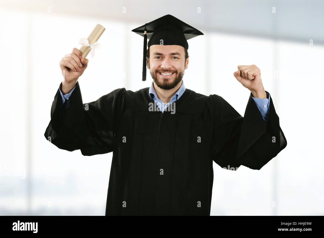 Allegro sorridente graduate indossando camice alla cerimonia di consegna dei diplomi Foto Stock