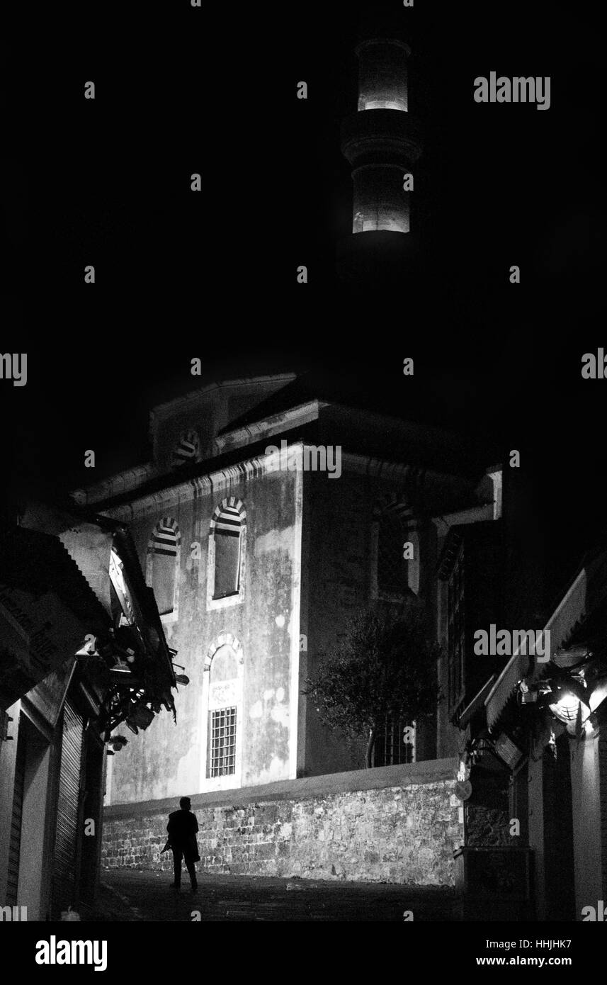 Uomo a camminare da soli alla ricerca di una grande parete di notte in una strada pedonale a Rodi, Grecia. Foto Stock