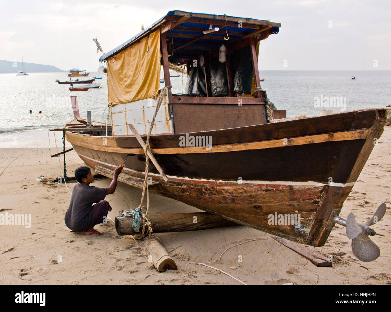 Fisherman pittura la sua barca in Phuket, Tailandia. Foto Stock