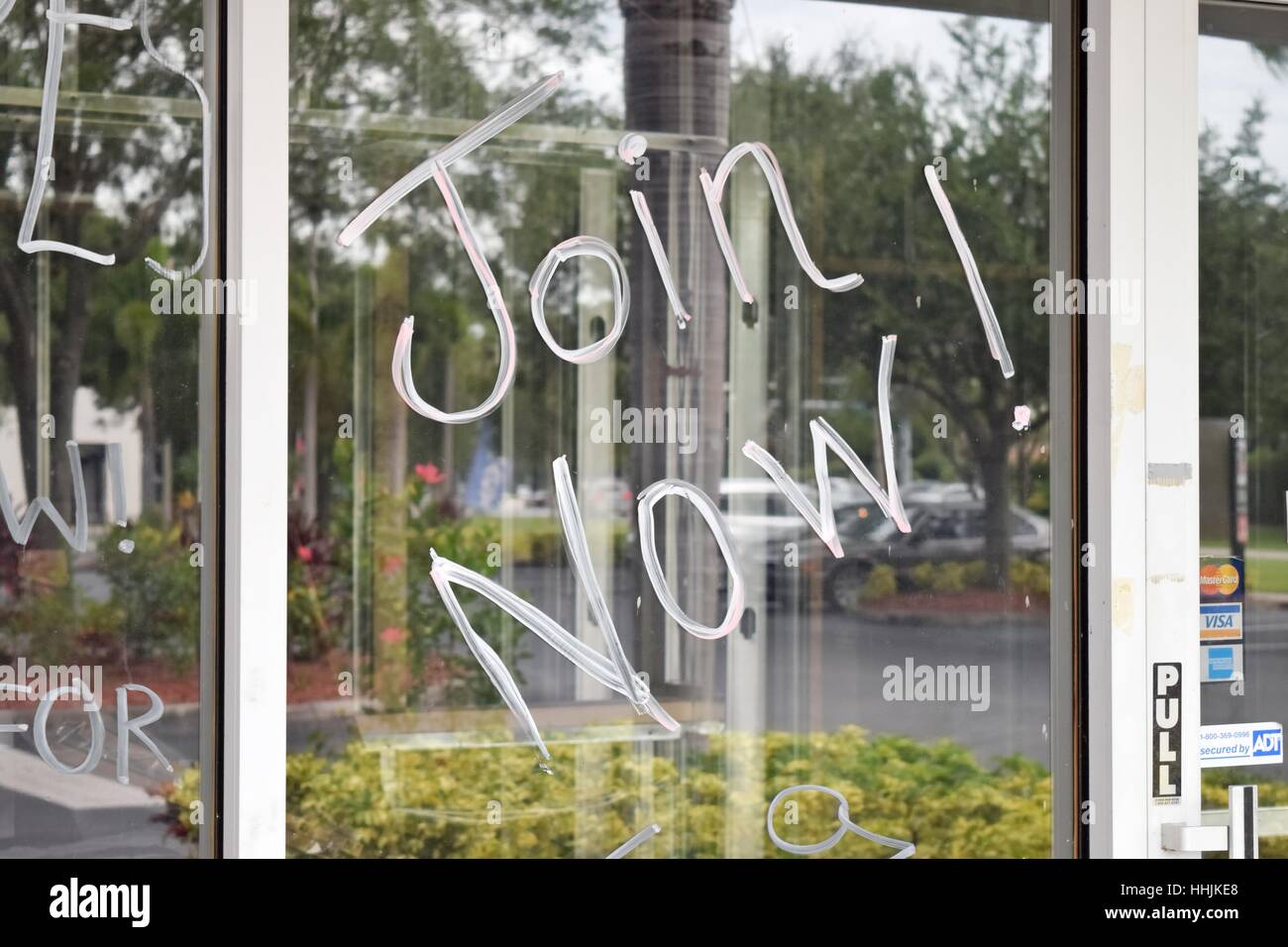"Join Now!", scritto in soap/vernice bianca su una finestra storefront per pubblicizzare una piccola apertura di business Foto Stock