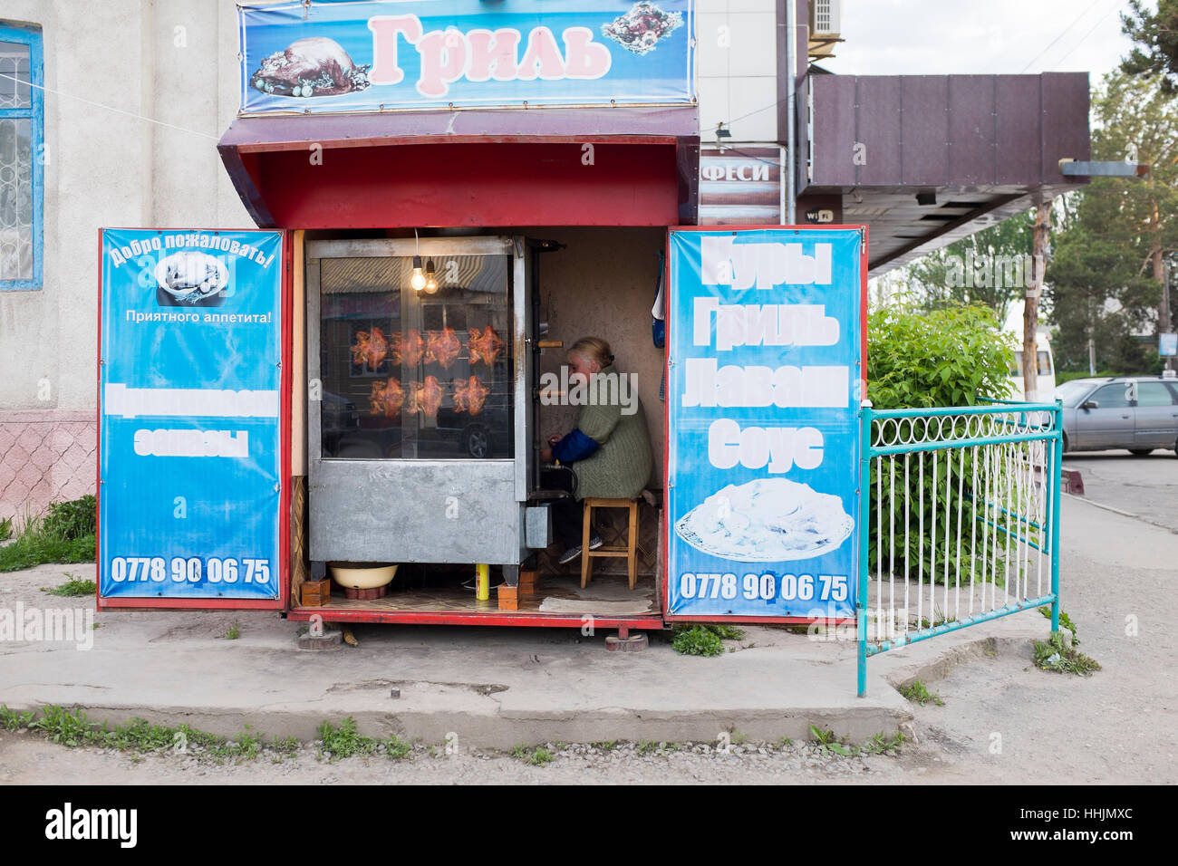 Una piccola cabina d'angolo che vende pollo rotisserie nella piccola città di Karakol nella parte orientale del Kirghizistan in Asia centrale. Foto Stock