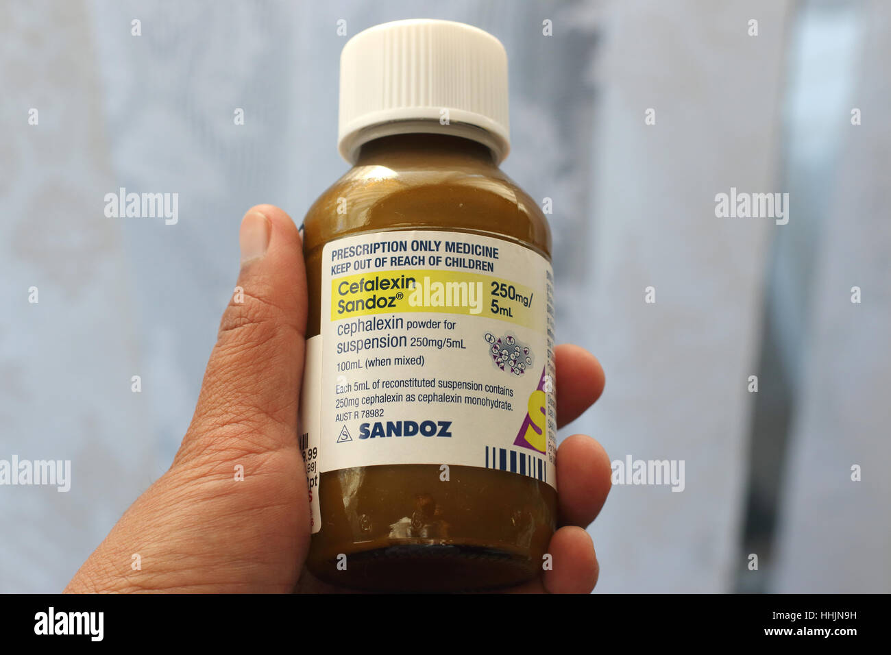 Mano che tiene la cefalexina Sandoz antibiotico Foto Stock