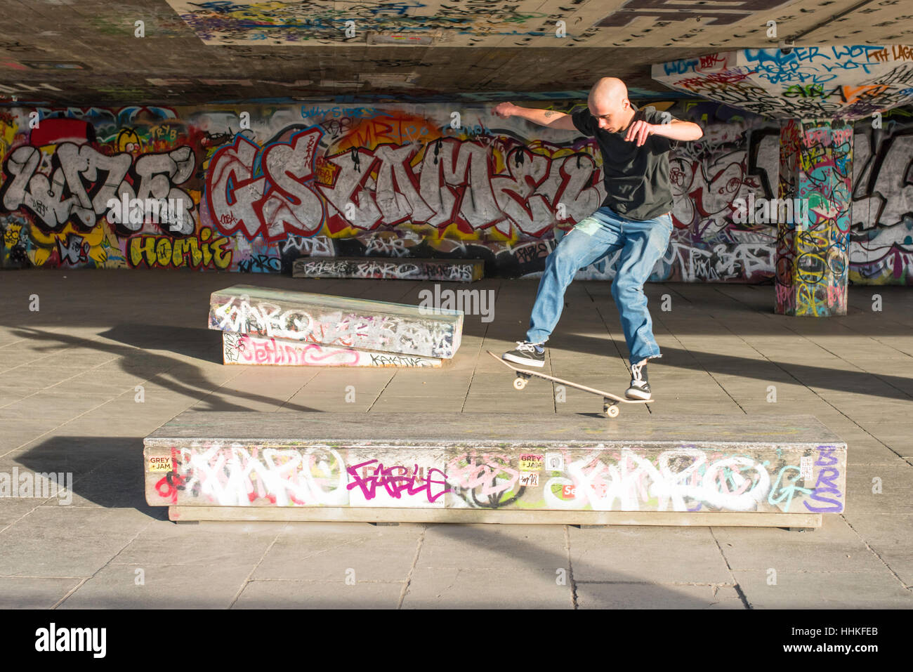 Un guidatore di skateboard calva effettuando un salto nel sottopassaggio presso il South Bank di Londra. Foto Stock