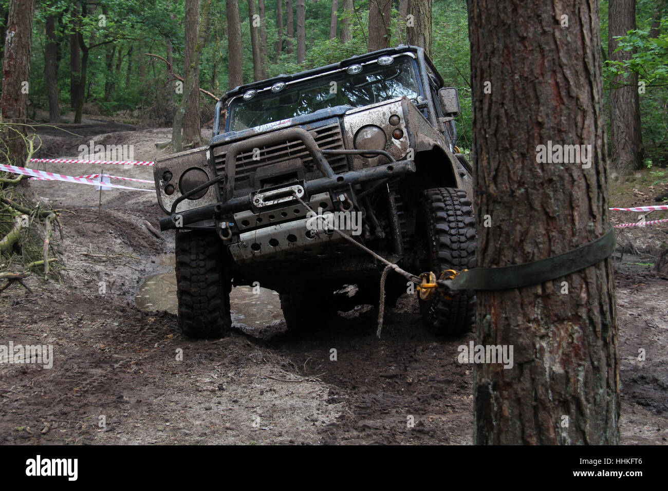 Blue 4x4 Land Rover Defender 90 winching durante un fangoso off-road challenge Foto Stock