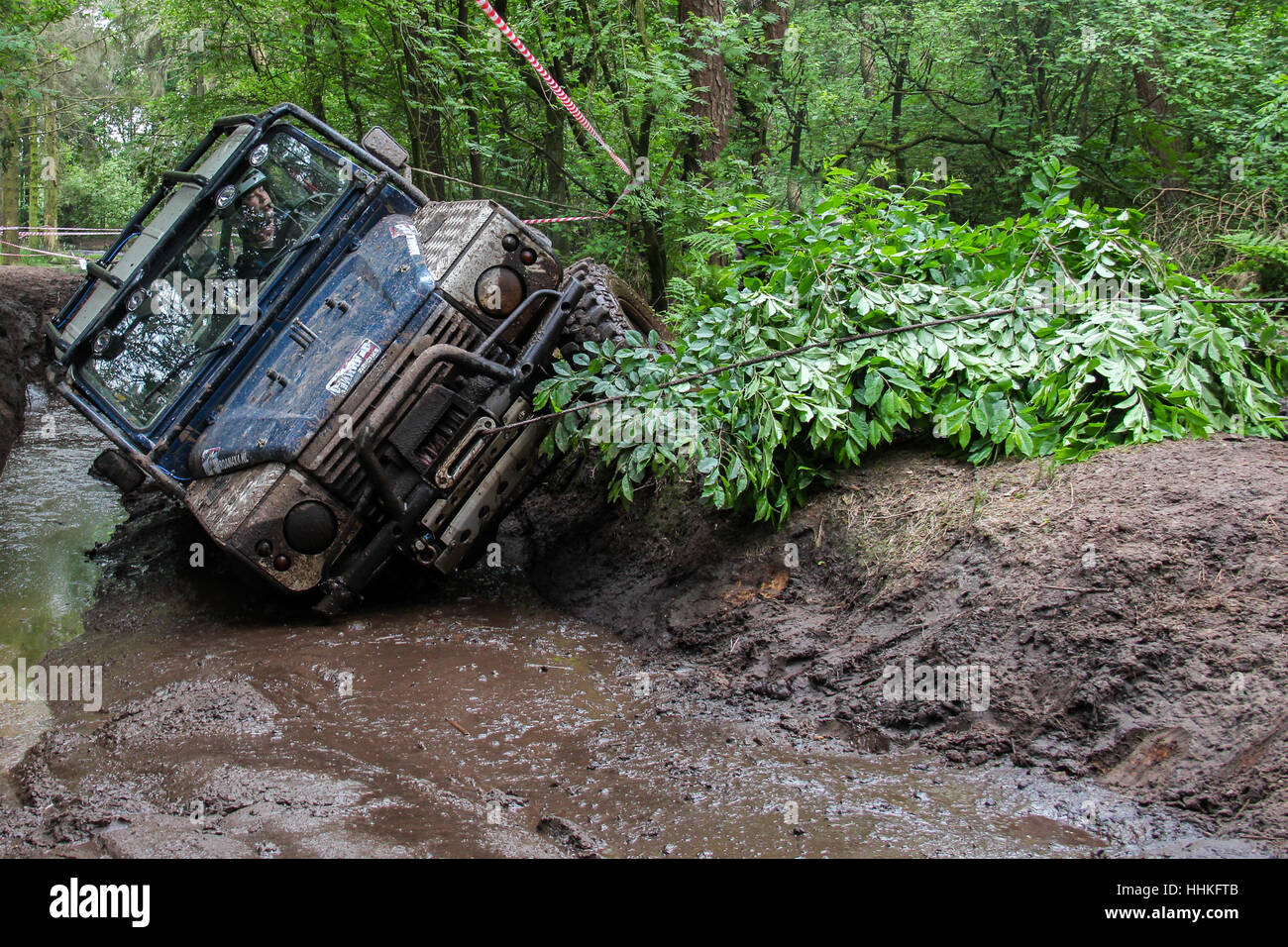 Blue 4x4 Land Rover Defender 90 winching durante un fangoso off-road challenge Foto Stock