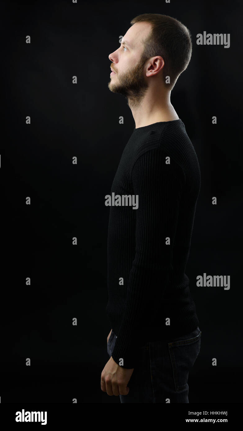 Ritratto di profilo di uomo barbuto guardando verso l'alto. Sfondo nero Foto Stock