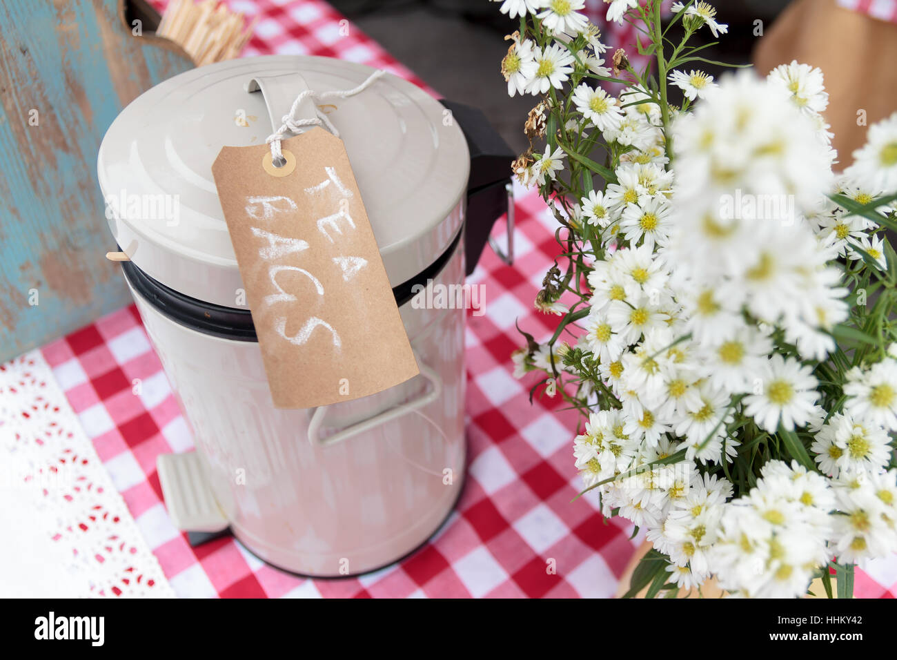 Lo stagno di bustine di tè con chalk tag seduto su un tavolo da picnic accanto a fiori Foto Stock