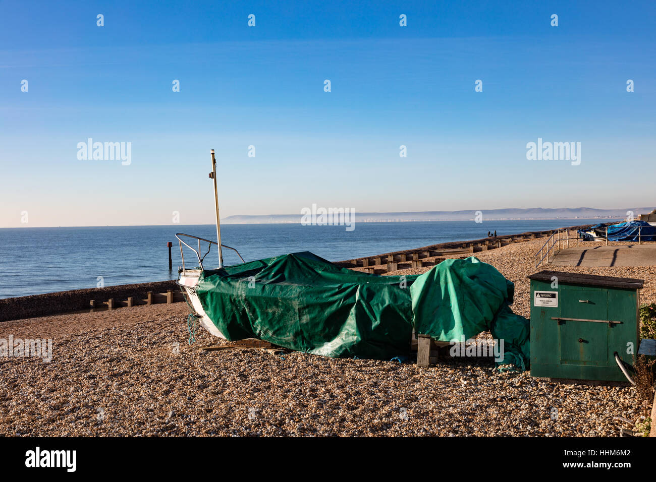 Barca coperta da un telone sulla spiaggia guardando verso Beachy Head e Eastbourne con nebbia distante, Stroud, East Sussex, Regno Unito Foto Stock