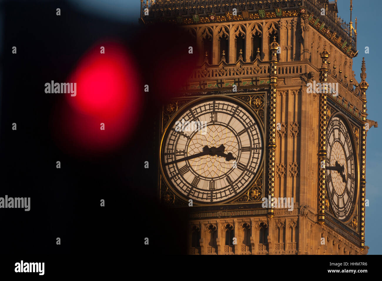 Un semaforo rosso in primo piano e il clockface contenente il Big Ben campana in Elizabeth Torre del parlamento britannico, il 17 gennaio 2017, a Londra Inghilterra. La torre di Elizabeth (precedentemente chiamato la Torre dell Orologio) denominata in omaggio alla Regina Elisabetta II nel suo Diamond anno giubilare - è stata sollevata come una parte di Charles Barry design per un nuovo palazzo, dopo che il vecchio Palazzo di Westminster fu in gran parte distrutto da un incendio durante la notte del 16 ottobre 1834 .. (Di più nella descrizione). Foto Stock