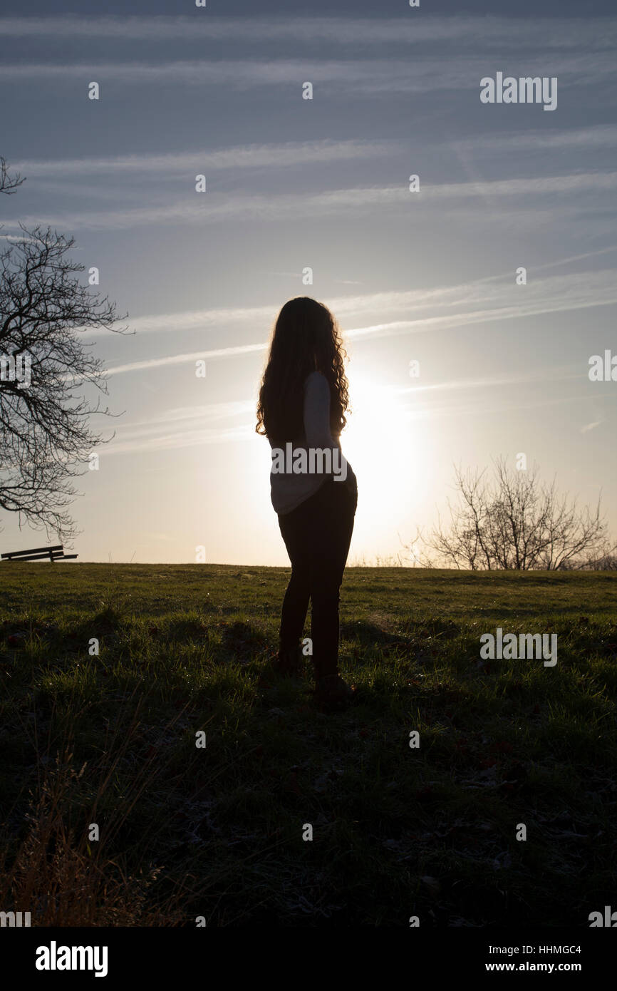 Silhouette di un irriconoscibile donna guardando il Cielo di tramonto. Vista posteriore. Foto Stock