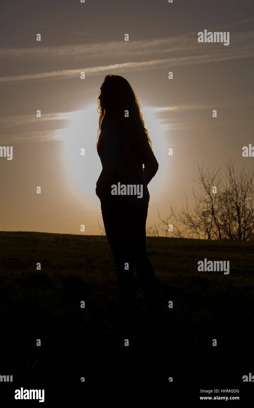 Irriconoscibile donna guardando il Cielo di tramonto. Silhouette, vista posteriore. Foto Stock