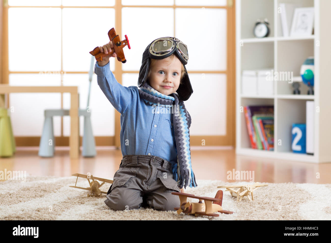 Bambino fingendo di essere aviatore. Kid giocando con gli aeroplani giocattolo a casa Foto Stock
