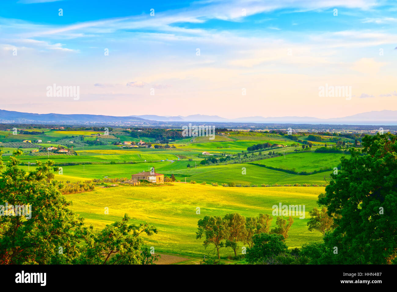 La Maremma, rurali paesaggio al tramonto. Fattoria di campagna e campi verdi. Isola d'Elba su orizzonte. Toscana, Italia, Europa. Foto Stock