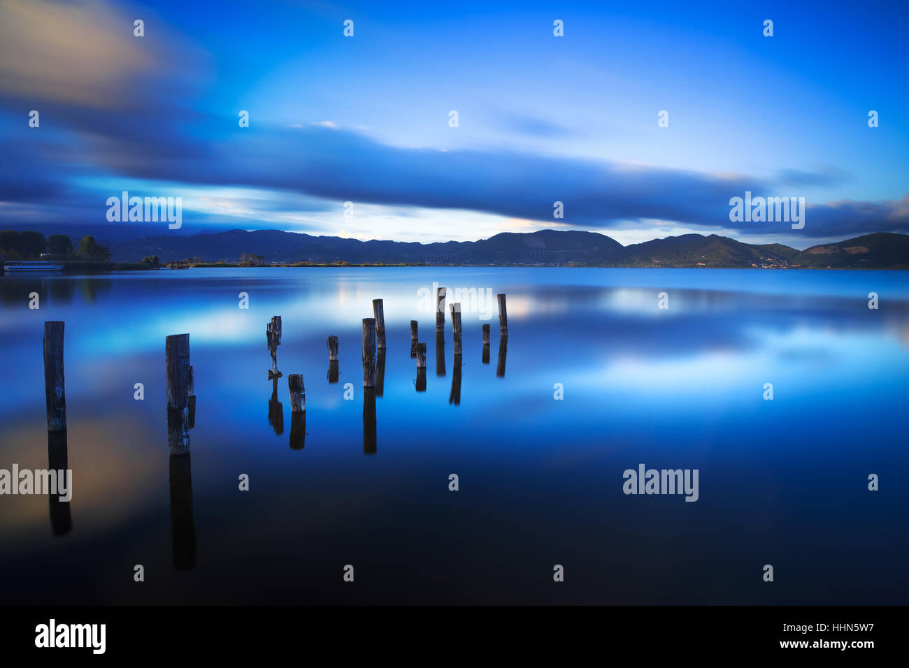 Il molo di legno o molo rimane sul lago blu tramonto Cielo e acqua di riflessione. Una lunga esposizione, Versilia Massaciuccoli, Toscana, Italia. Foto Stock
