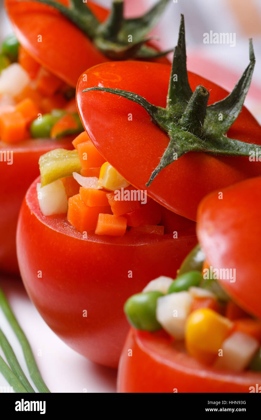 Cibo vegetariano: pomodori ripieni con verdure fresche. macro verticale. Foto Stock