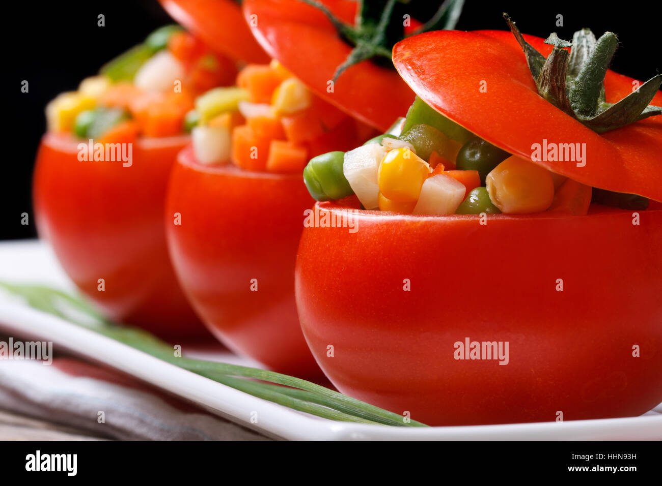 Cibo vegetariano: pomodori ripieni con verdure fresche. macro. orizzontale. chiave di basso Foto Stock