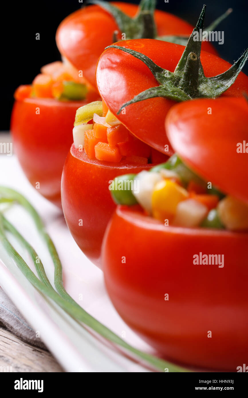 Cibo vegetariano: pomodori ripieni con verdure fresche su uno sfondo scuro. macro. verticale. Foto Stock