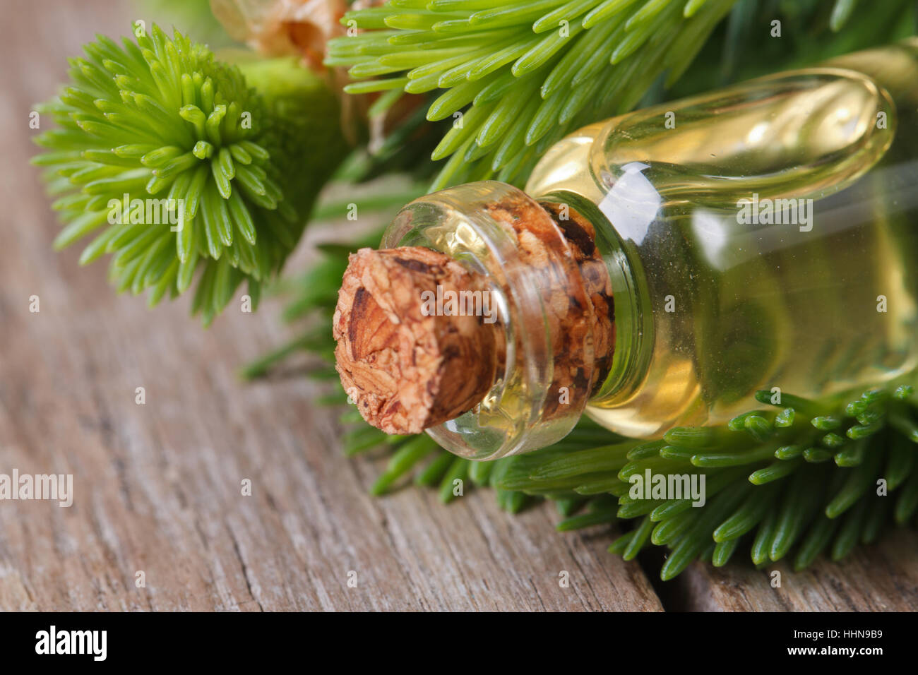 Olio aromatico di abete e giovani rami closeup su una tavola di legno orizzontale. Foto Stock