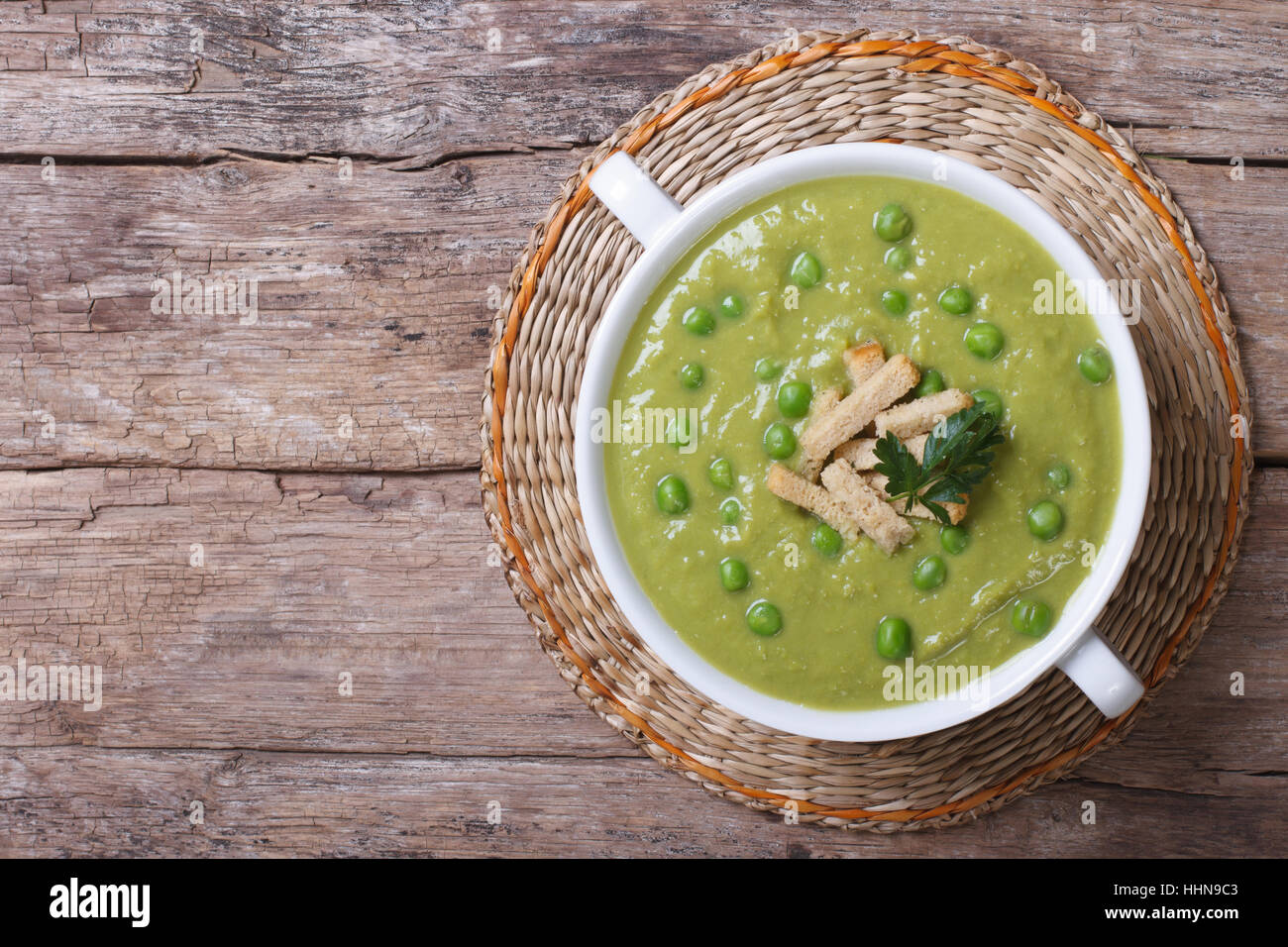 Verde la zuppa di piselli con crostini sul vecchio tavolo. vista superiore Foto Stock