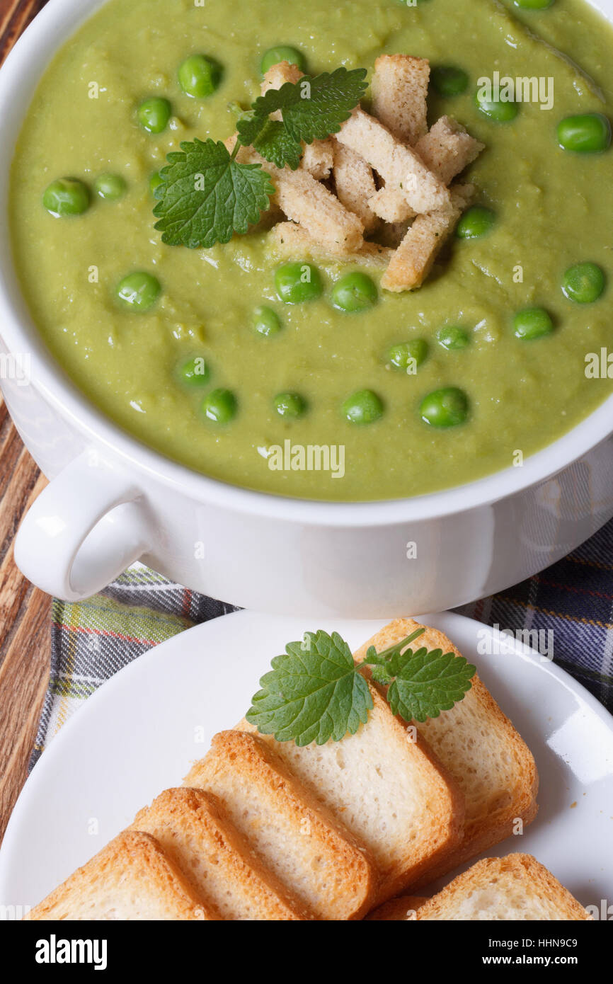 Verde la zuppa di piselli con crostini e menta closeup. vista dall'alto in verticale Foto Stock